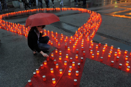 A Serbian woman lights a candle placed on a symbolic red ribbon in remembrance of individuals who lost their lives to AIDS in Belgrade, on May 15, 2011. AFP PHOTO / ALEXA STANKOVIC (Photo credit should read ALEXA STANKOVIC/AFP/Getty Images)