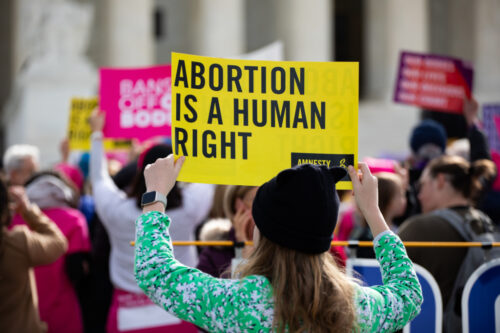 devojka sa transparentom na protestu za pravo na abortus